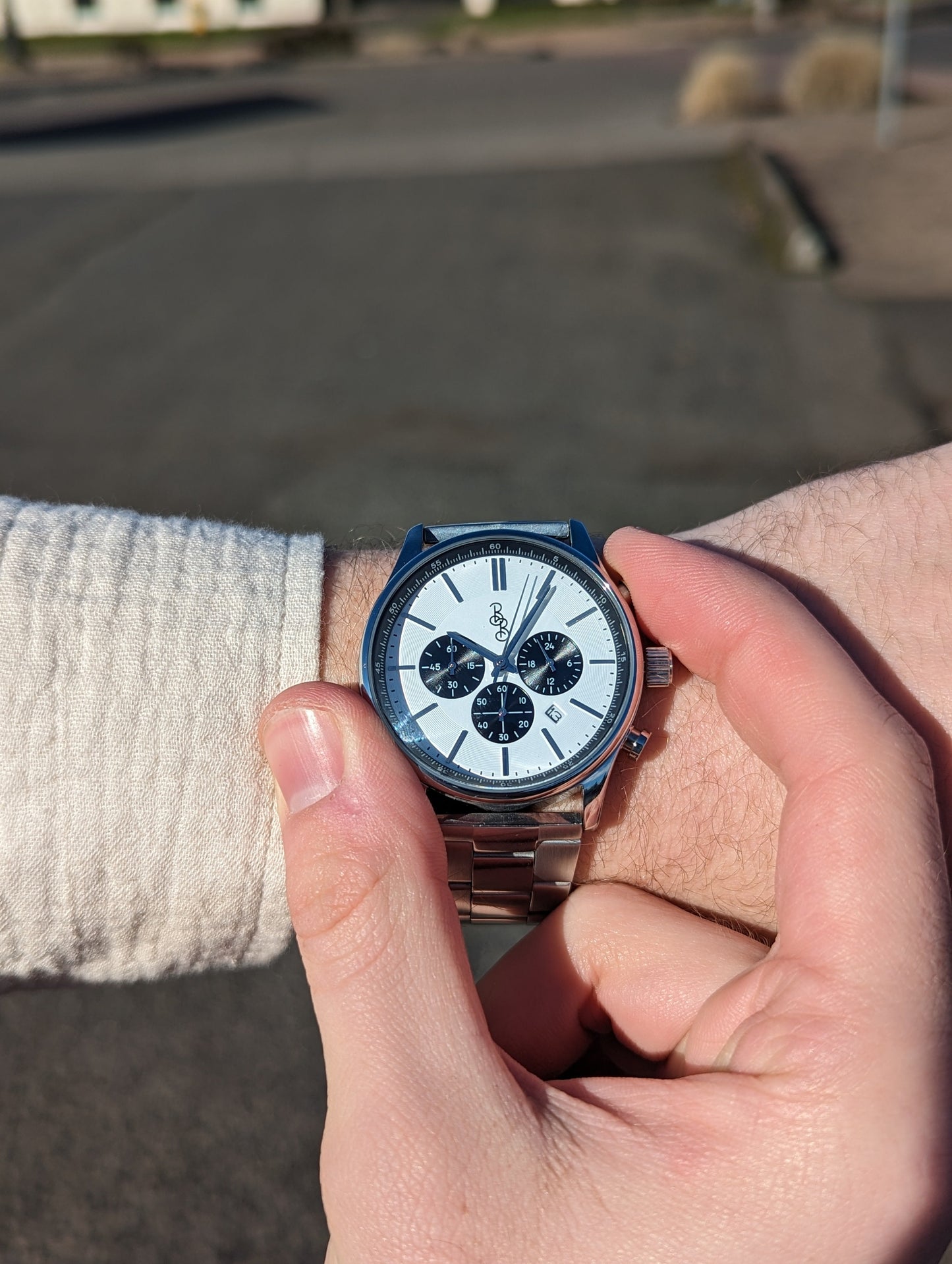Adjusting time on white and black chronograph wristwatch lifestyle shot