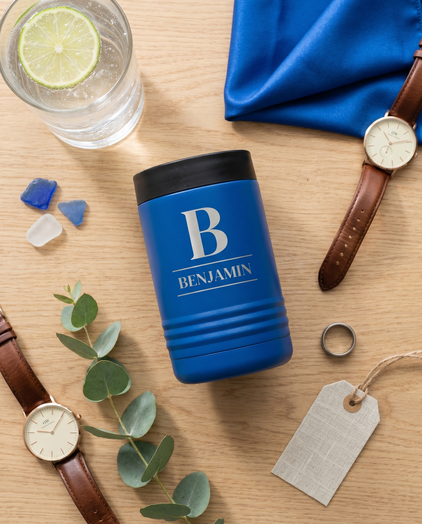 Personalized royal blue stainless steel insulated can cooler flat lay with gin and tonic and leather watch