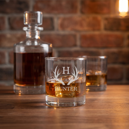 Engraved Barrel Decanter Set lifestyle - close-up of HUNTER antler engraved lowball whiskey glass with decanter in background