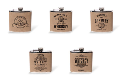 All five whiskey label engraving designs shown on leather wrapped flasks