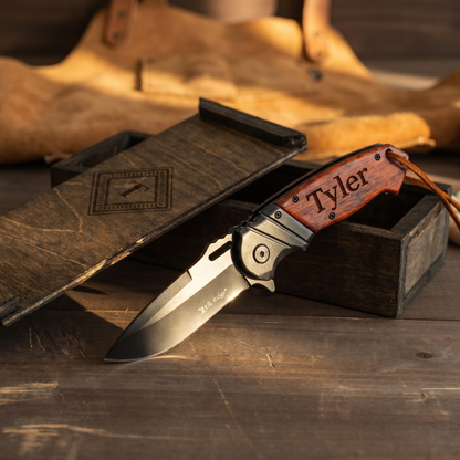Personalized red handle pocket knife blade detail with leather workshop apron backdrop