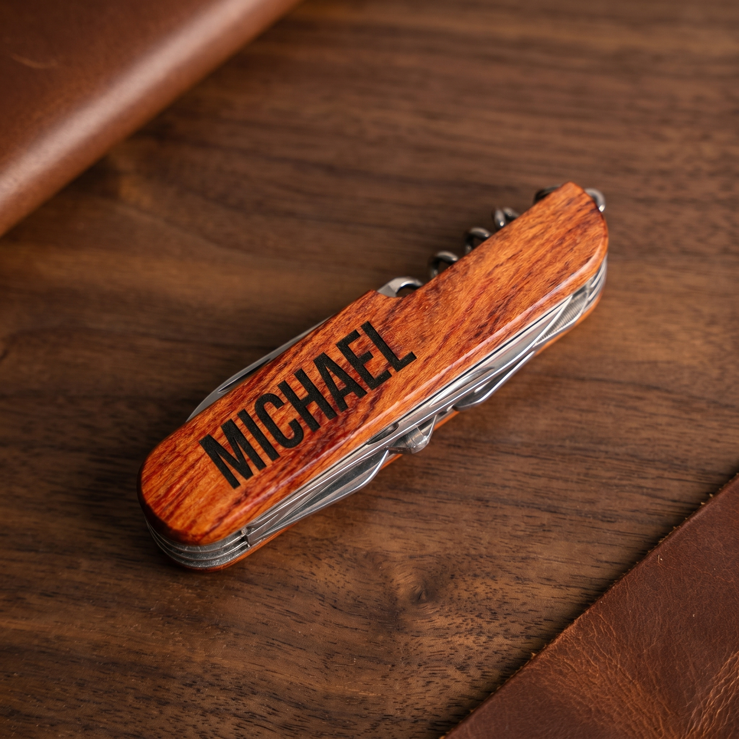 Personalized wood-handled multitool pocket knife with engraved name on walnut surface